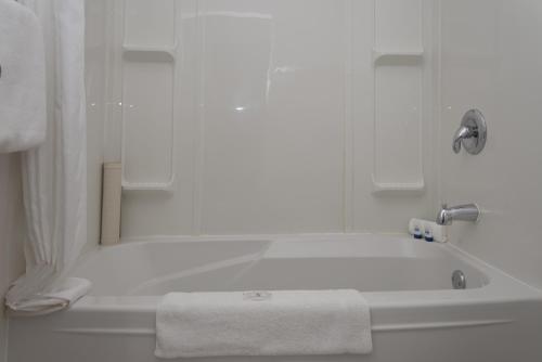 a white bathroom with a bath tub with a towel at Valley Star Motel in Penticton