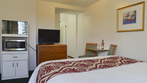 a hotel room with a bed and a flat screen tv at Valley Star Motel in Penticton