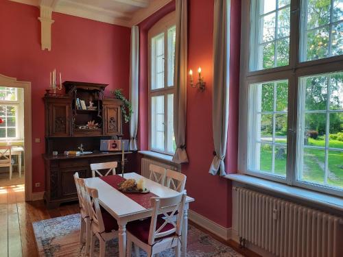 ein Esszimmer mit roten Wänden sowie einem Tisch und Stühlen in der Unterkunft Kamin-Stuuv in Stubbendorf