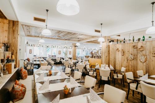 a restaurant with white tables and chairs and wooden walls at Vitalhotel Gosau in Gosau