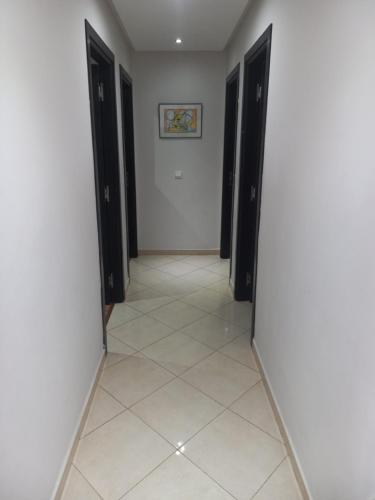 a hallway with black doors and a tile floor at Appt Bab Rayane Uniquement pour les familles in Casablanca