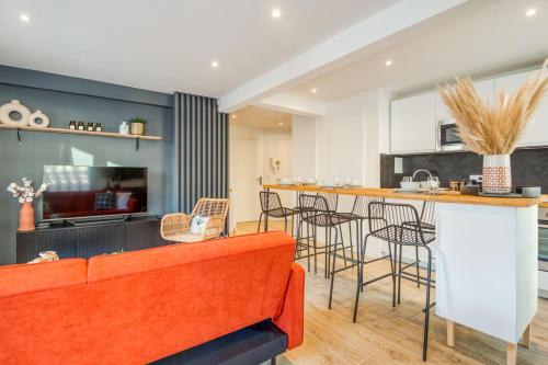 a living room with an orange couch and a kitchen at Appartement Wilsonia - Welkeys in Antibes