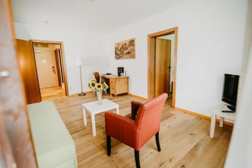 a living room with a red chair and a table at Vitalhotel Gosau in Gosau
