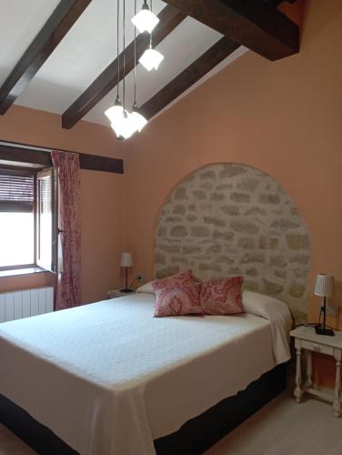 1 dormitorio con 1 cama grande y cabecero de piedra en Inma Enea en Armañanzas