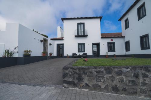 a white house with a stone wall in front of it at Vila Rosario in Ponta Delgada