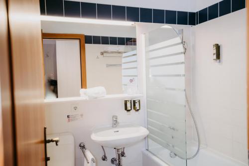 a white bathroom with a sink and a mirror at Vitalhotel Gosau in Gosau
