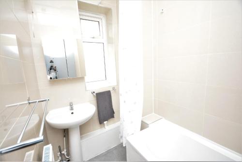 a white bathroom with a sink and a mirror at Beautiful London 2 Bedroom Flat near Finsbury Park in London