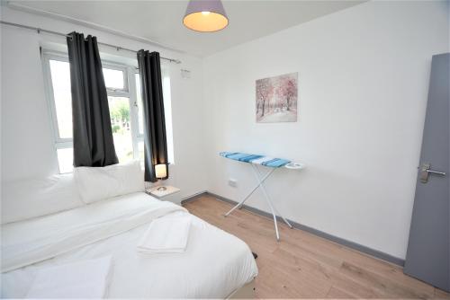 um quarto branco com uma cama e uma janela em Beautiful London 2 Bedroom Flat near Finsbury Park em Londres