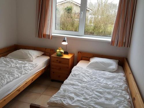 two beds in a room with two windows at Mees in Hollum
