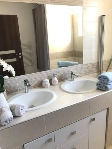 une salle de bain avec deux lavabos et un grand miroir dans l'établissement maison cosy climatisée avec piscine et jardin, à Calenzana