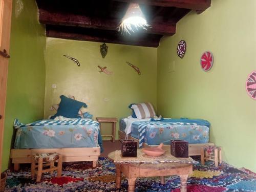 - une chambre pour enfants avec 2 lits et une table dans l'établissement Auberge lac d'ifni, à Aoulouz