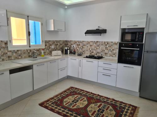 uma cozinha com armários brancos e um tapete no chão em Villa Bleue plage Sonia em Zarzis