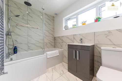 y baño con bañera, lavamanos y ducha. en 3Bed 2Bath House Contractors Accommodation free Parking WiFi Stevenage Hertfordshire Self Catering Sleeps 6 Guests By White Orchid Property Relocation, en Stevenage