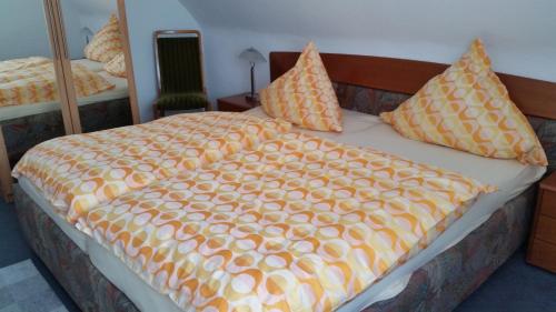 ein Bett mit einer orangefarbenen Bettdecke und Kissen darauf in der Unterkunft Ruheoase in Hattingen