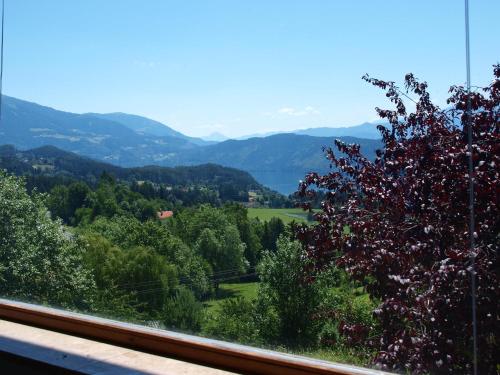 a window with a view of a field and mountains at Haus am Hügel in Millstatt