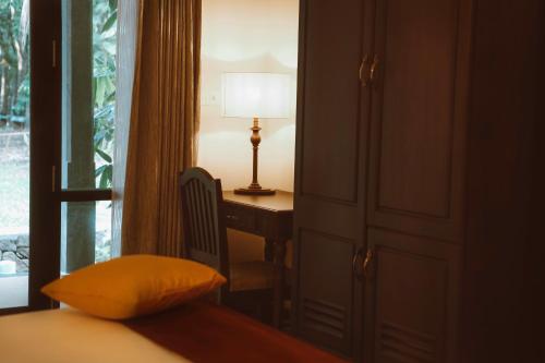 a bedroom with a desk and a bed with a lamp at Vaikundam Legacy in Kaliyal