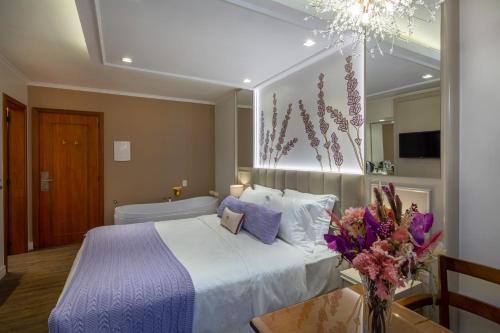 a bedroom with a bed and a table with a vase of flowers at Blumen Hotel Boutique in Canela