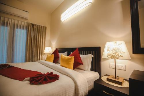 um quarto com uma cama grande com almofadas vermelhas e amarelas em Vaikundam Legacy em Kaliyal