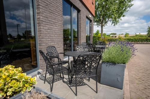a patio with black chairs and a table and flowers at Bastion Hotel Leeuwarden in Leeuwarden
