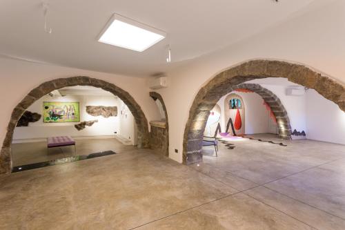 an empty room with stone archways and a room with paintings at Palazzo Previtera Hotel & Restaurant in Linguaglossa
