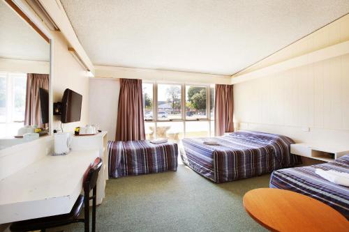 a hotel room with two beds and a desk at Sunnybank Hotel Brisbane in Brisbane