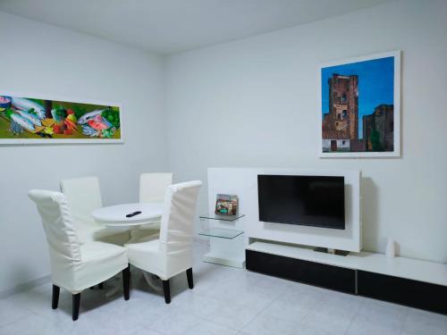 een witte kamer met een tafel en stoelen en een televisie bij Casa Rosales Toledo a 10 minutos de Puy du Fou in Polán