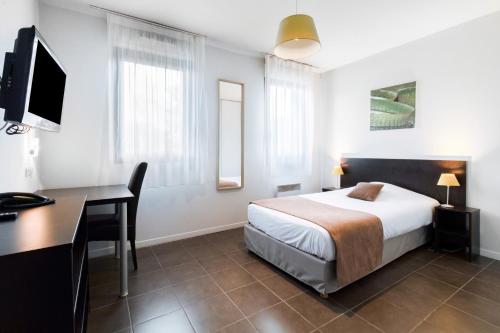 a bedroom with a bed and a desk and a computer at All Suites Pau – Zénith in Pau