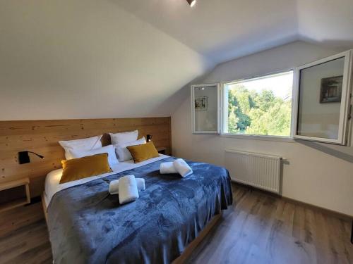 1 dormitorio con 1 cama grande con sábanas azules y ventana en La cabane des écureuils, en Xonrupt-Longemer