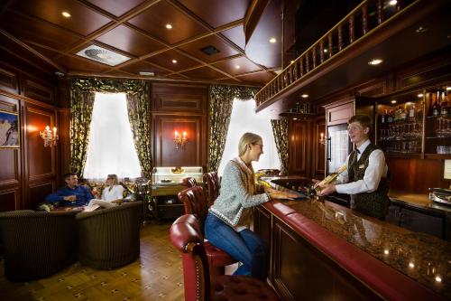 a man and a woman standing at a bar at Luxury Family Hotel Royal Palace in Prague