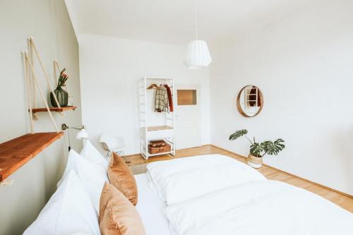 Central Design-Apartment next to Belvedere Castle في فيينا: غرفة نوم بجدران بيضاء وسرير بمخدات