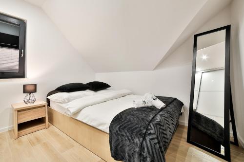 ein weißes Schlafzimmer mit einem Bett und einem Spiegel in der Unterkunft Domki Pod Lasem MM in Rabka-Zdrój