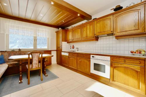 a kitchen with wooden cabinets and a table and a window at Chalet H Montafon in Gaschurn