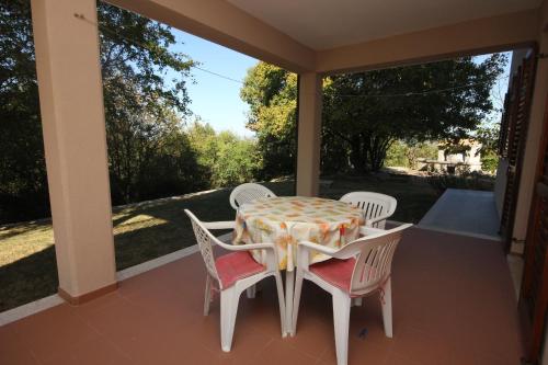 a table and chairs on a porch with a view of the yard at Apartments with a parking space Presika, Labin - 7390 in Labin