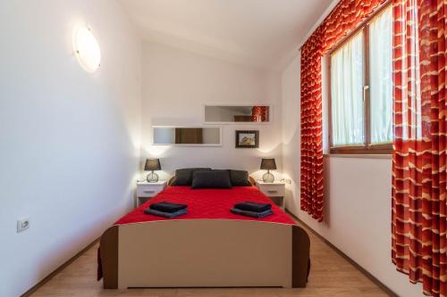 una camera con un letto con una coperta rossa di Family friendly apartments with a swimming pool Krnica, Marcana - 7357 a Krnica