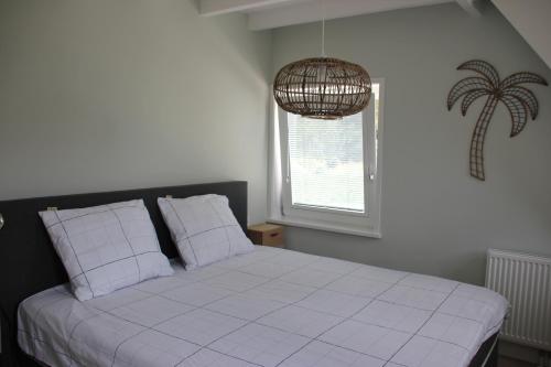 een slaapkamer met een bed met witte lakens en een raam bij Lodge21Ouddorp in Ouddorp
