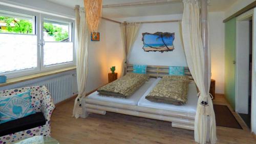 a bedroom with a canopy bed and two windows at Haus der 5 Kontinente in Böbrach