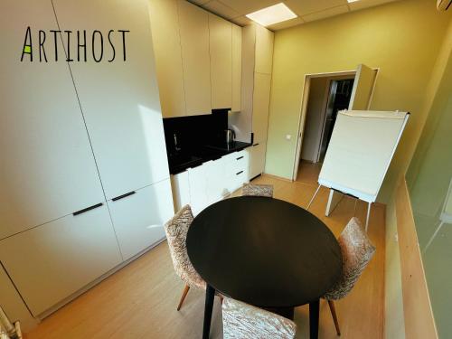 an office with a black table and chairs and a kitchen at Artihost in Panevėžys