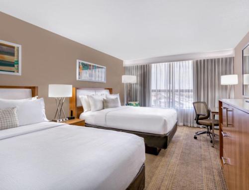 a hotel room with two beds and a desk at Holiday Inn Miami West - Airport Area by IHG in Hialeah Gardens