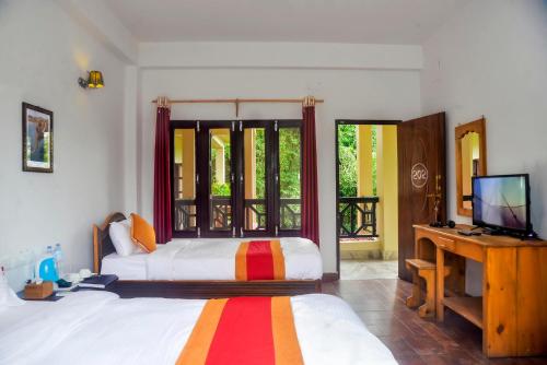 um quarto com uma cama e uma televisão num quarto em Chitwan Park Village em Sauraha