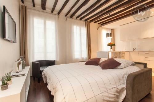 une chambre avec un grand lit blanc et une chaise dans l'établissement Montorgueil beautiful apartment, à Paris