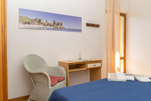 a room with a bed and a chair and a desk at Casa Secci in Santa Maria Navarrese
