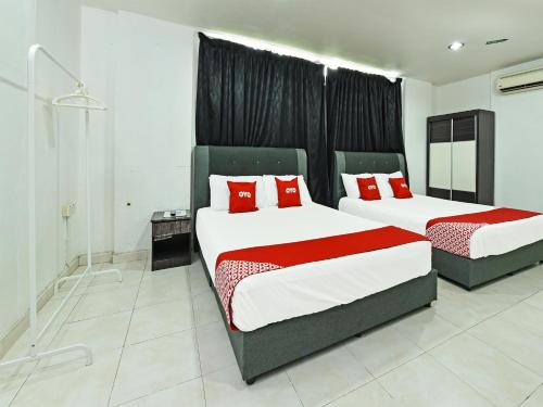 two beds in a hotel room with red pillows at Super OYO 90364 Hotel Gemilang in Kuala Terengganu