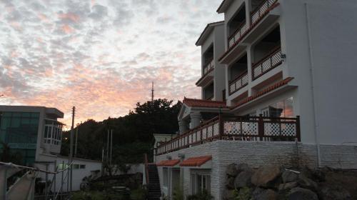 a white building with a sunset in the background at Good Day Pension in Seogwipo
