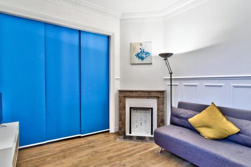 un salon avec un canapé bleu et une cheminée dans l'établissement Studio Quinault - Welkeys, à Paris