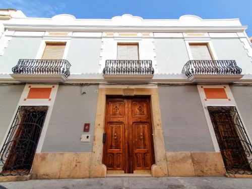 Edificio blanco con puertas de madera y 2 balcones en CASA BAUTISTA TURIS en Turís