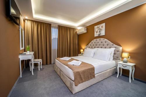 a hotel room with a large bed and two tables at Hotel Rivera in Dobrich