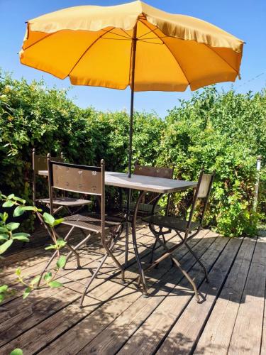 a table with a yellow umbrella and two chairs at Charmant gîte duplex du bon accueil in Trôo