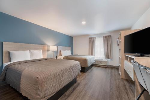 a hotel room with two beds and a flat screen tv at WoodSpring Suites Concord-Charlotte Speedway in Concord