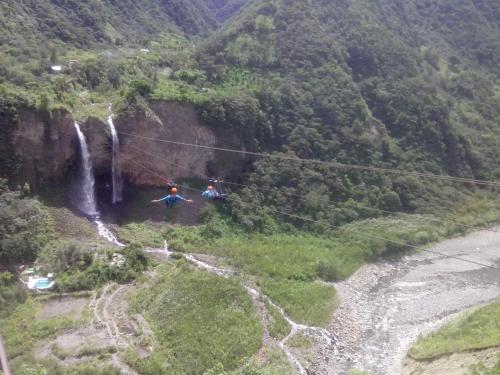 two people on a zip line in front of a waterfall at Hostal & Spa Casa Real in Baños