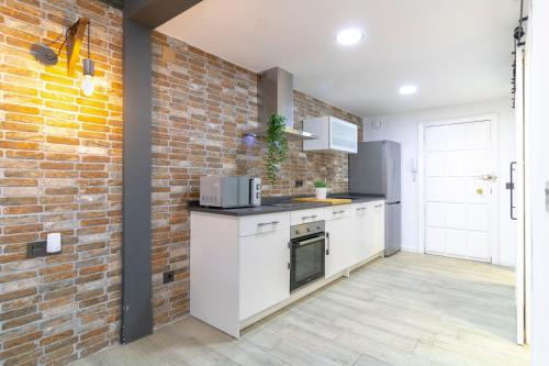 a kitchen with white cabinets and a brick wall at Acogedor Loft Bazán - Alicante Centro in Alicante